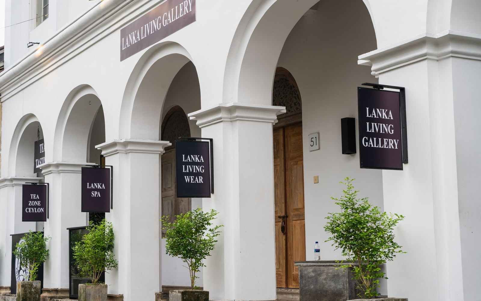 White colonnaded storefront with arched entrances and shop signs including Lanka Living Gallery