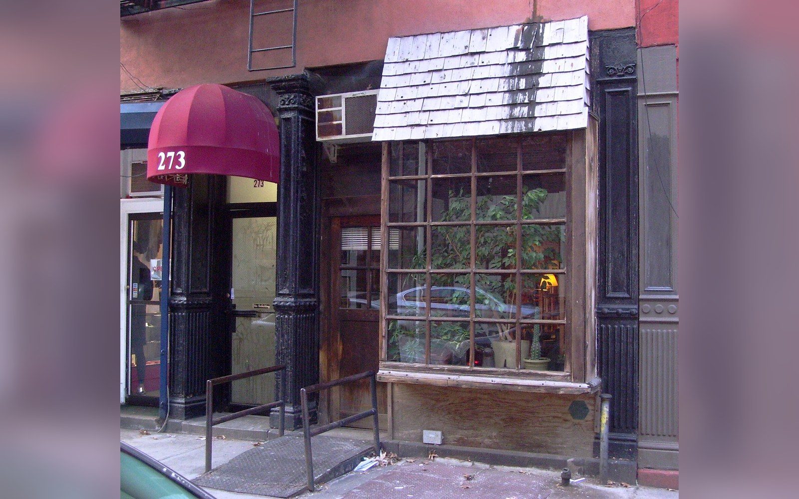 Storefront at 273 with a red awning and shingled wooden bay window extension