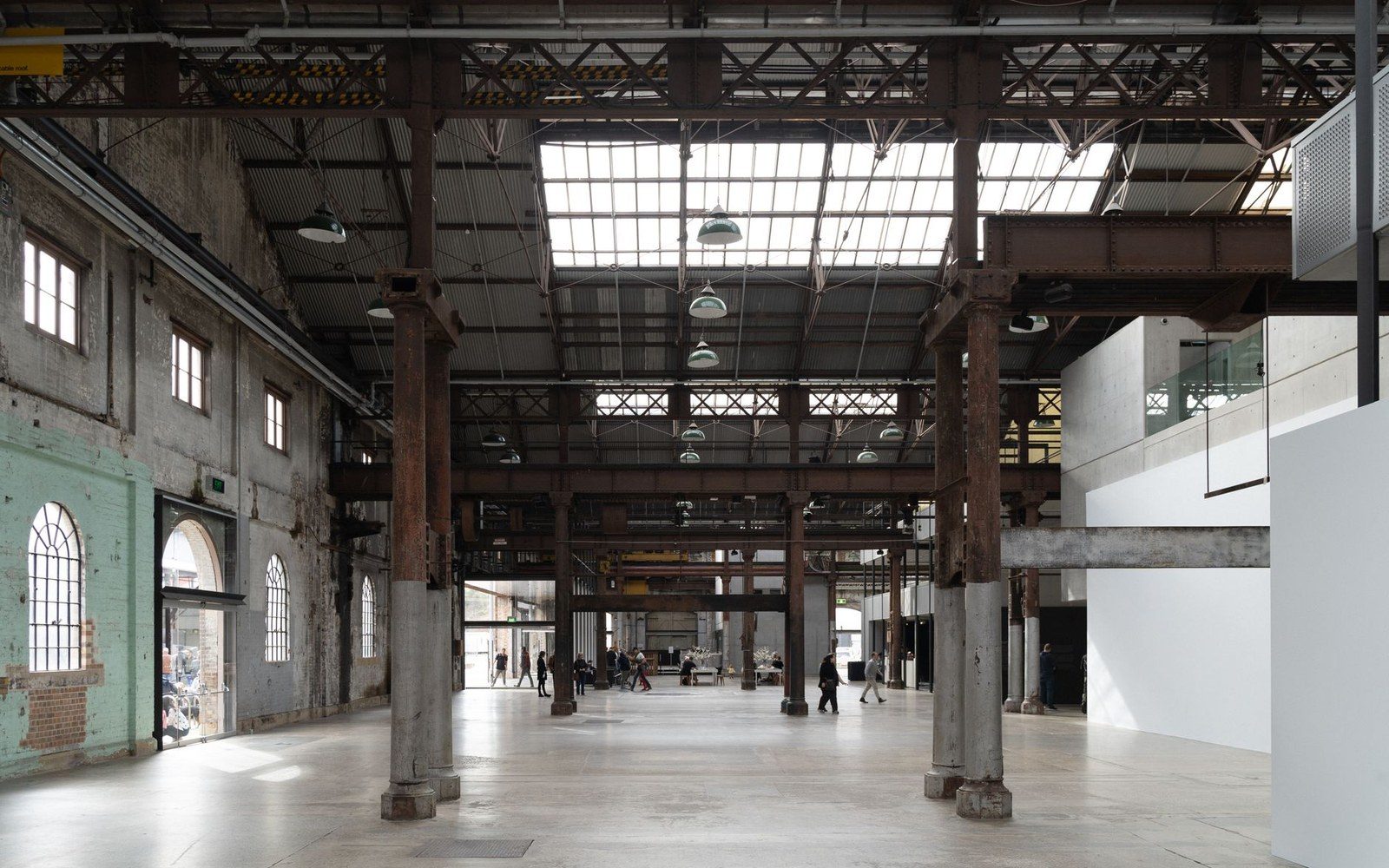 Converted industrial warehouse with exposed steel columns and skylights houses gallery visitors below