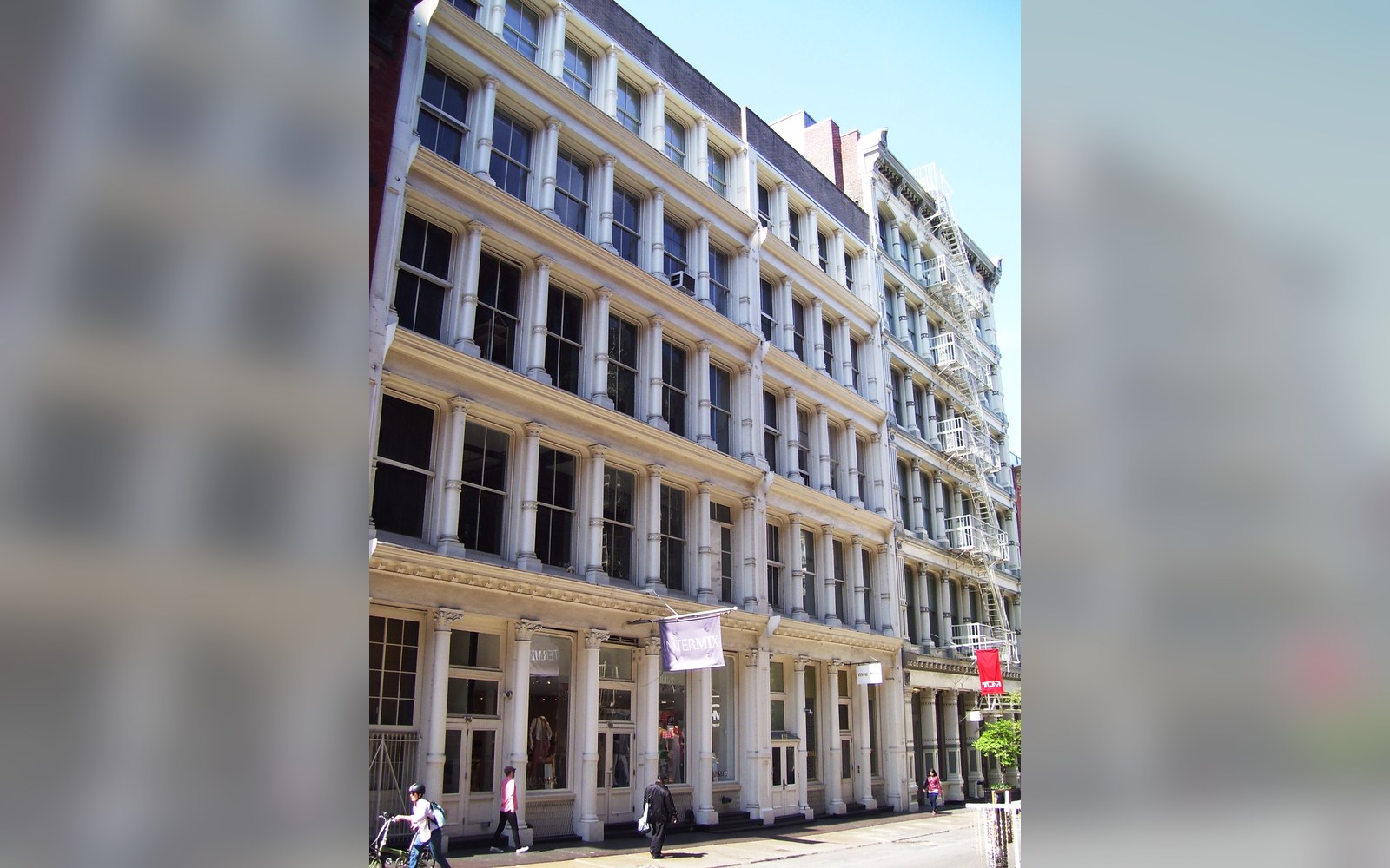 Cast-iron facade building with arched windows lines a Prince Street sidewalk